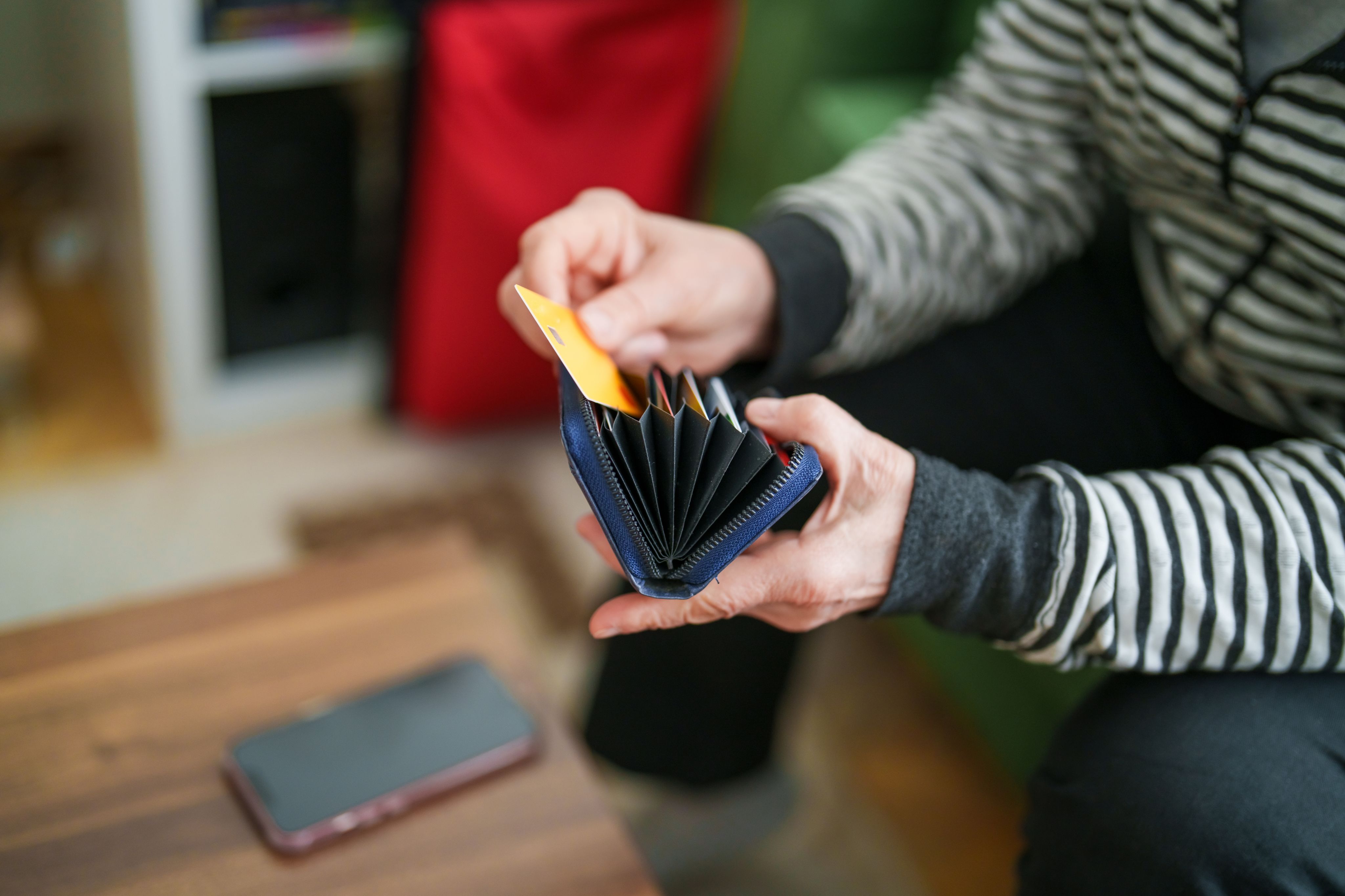 A woman pulls out a bank card as she looks through her wallet.
