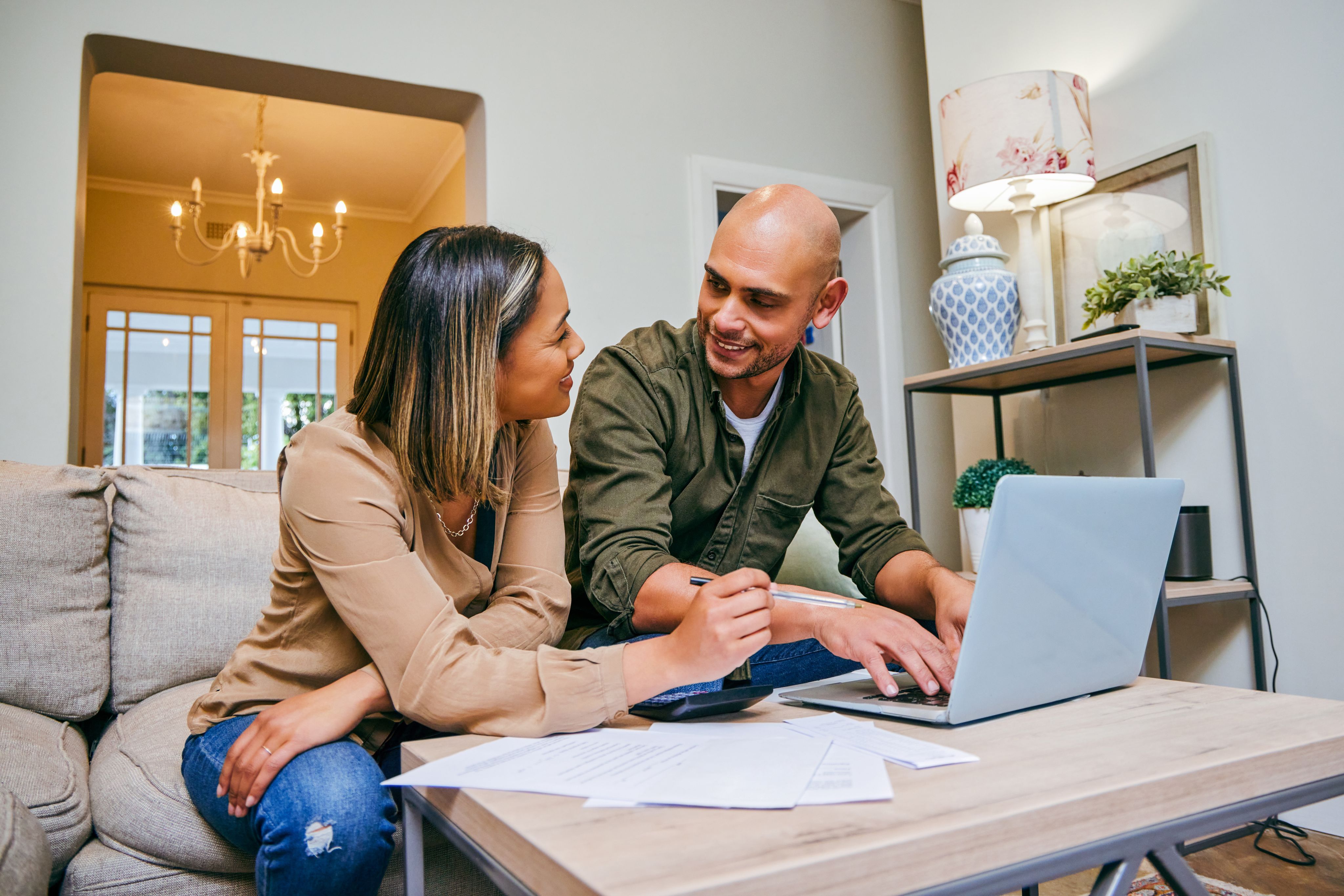 A couple work on their bills together at home using a laptop.