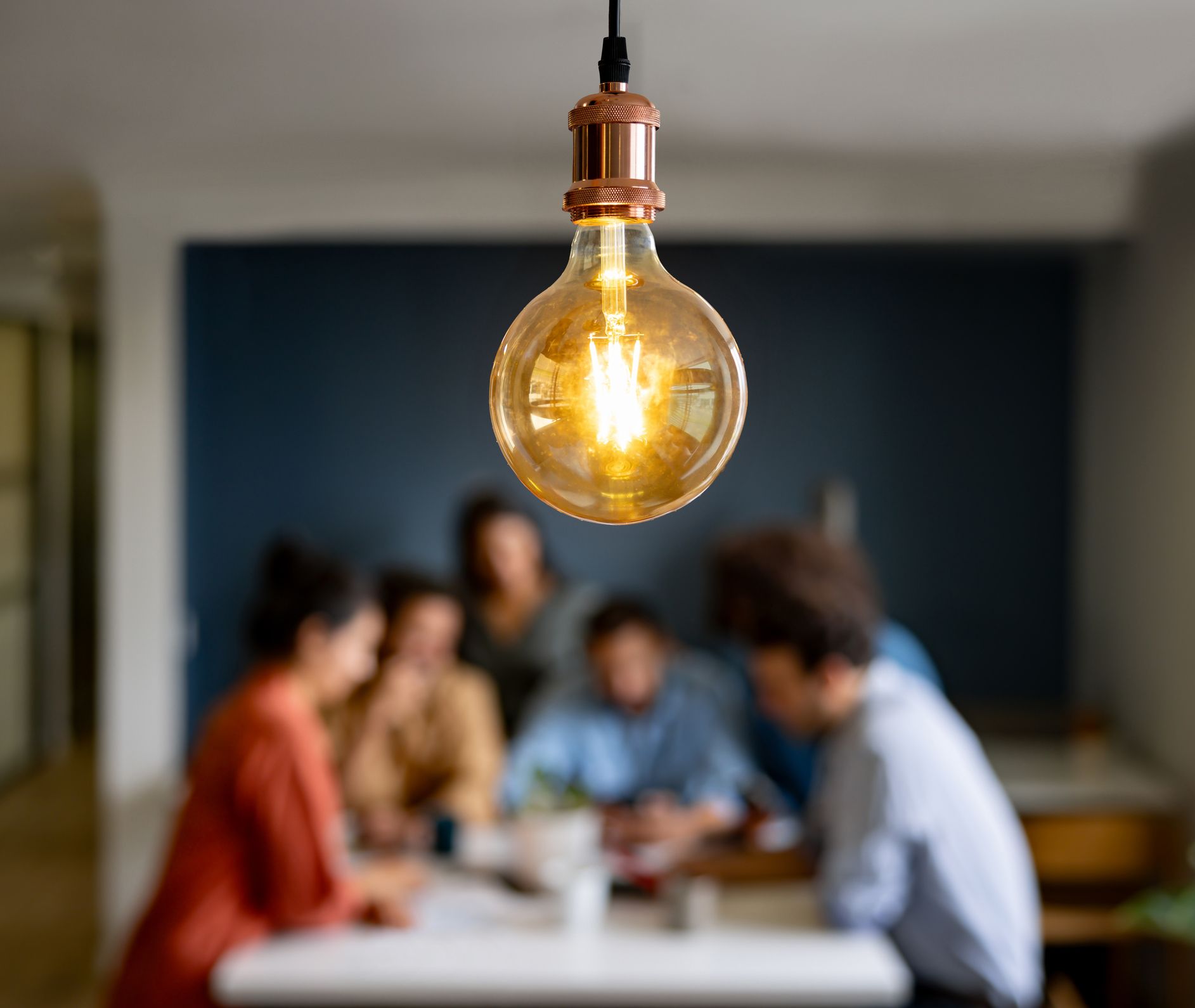 Image shows staff having a meeting with a bright light bulb shining