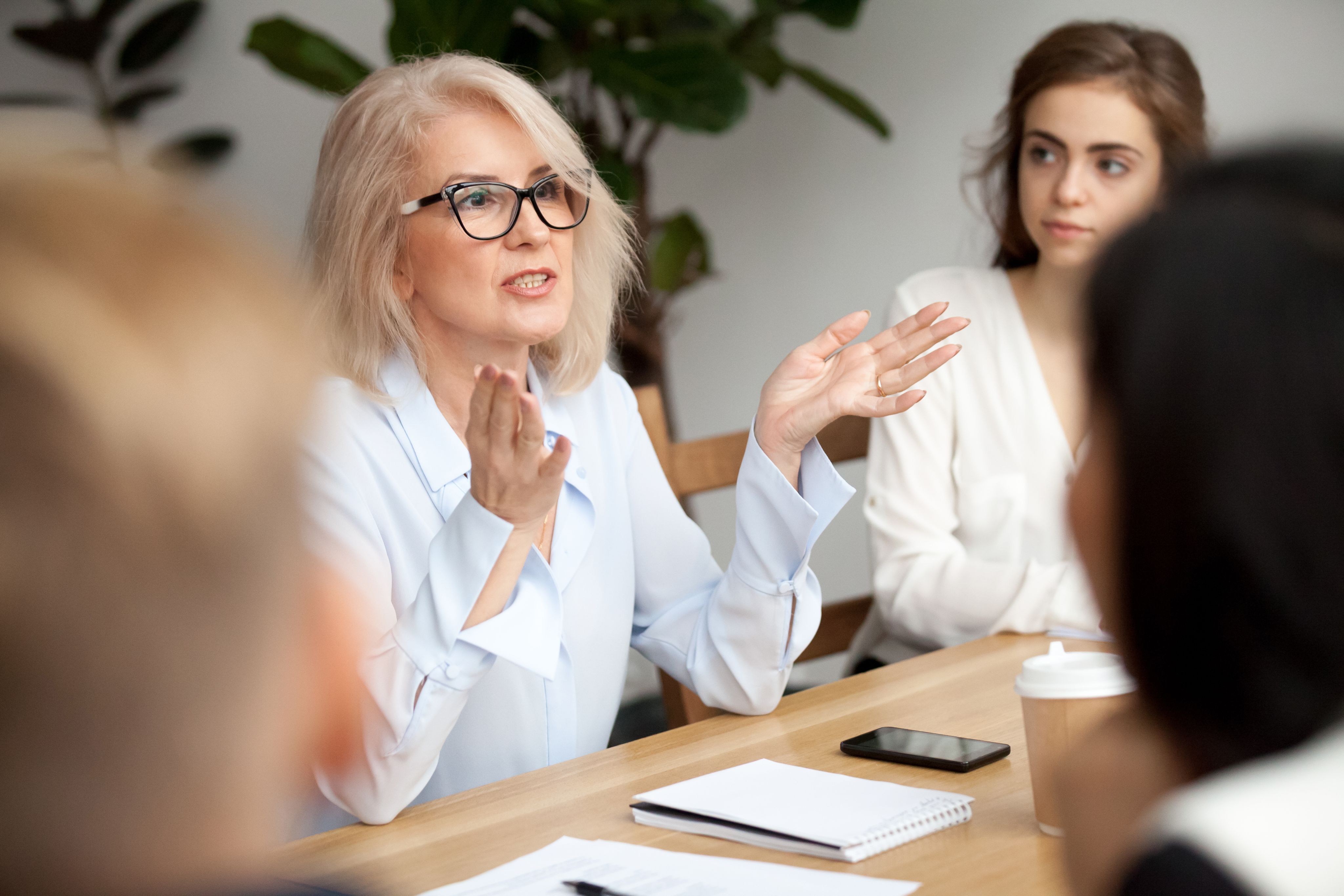 Image shows a woman speaks animatedly at a business meeting